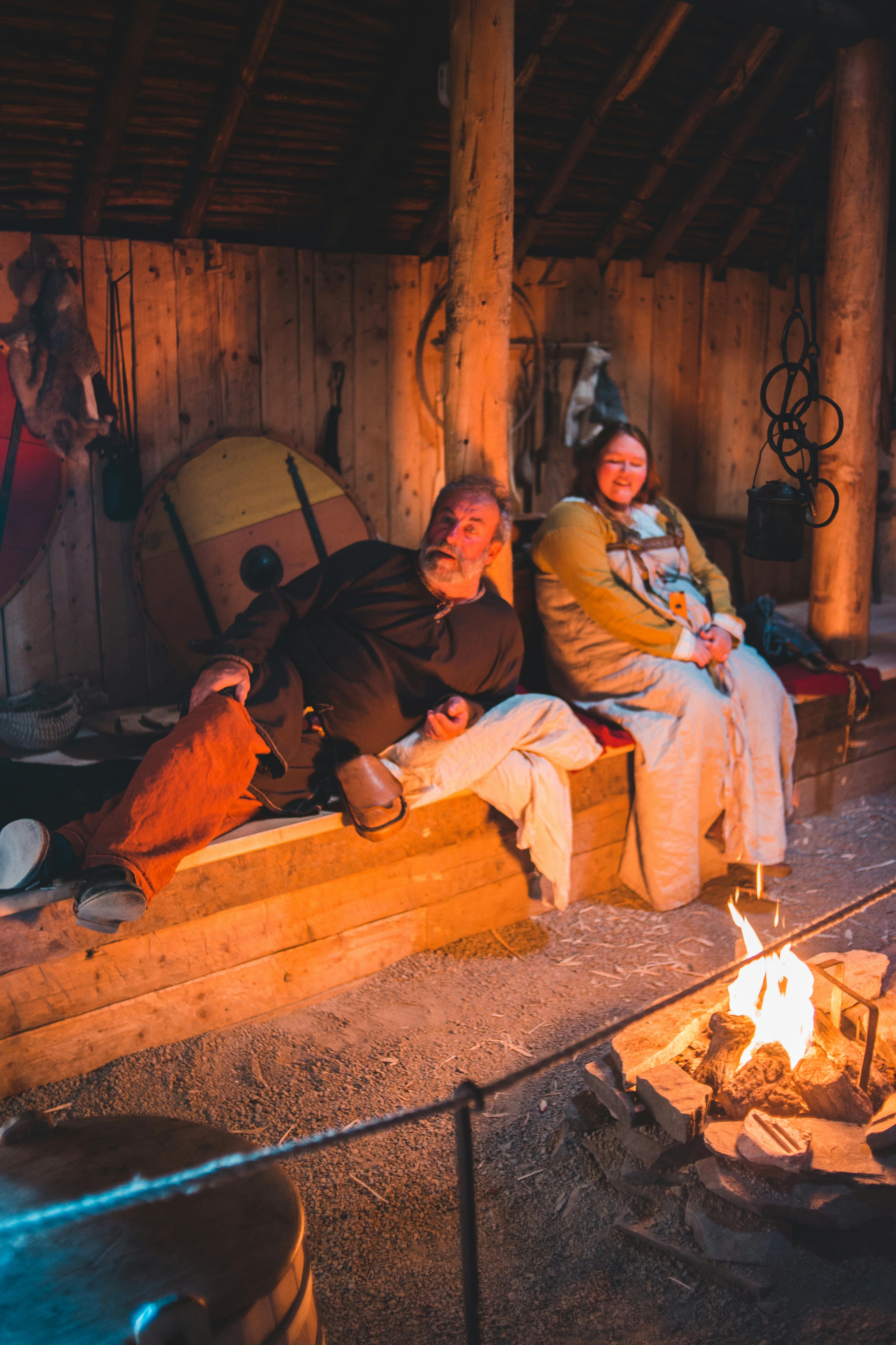 positive mature couple resting in cozy camp near bonfire