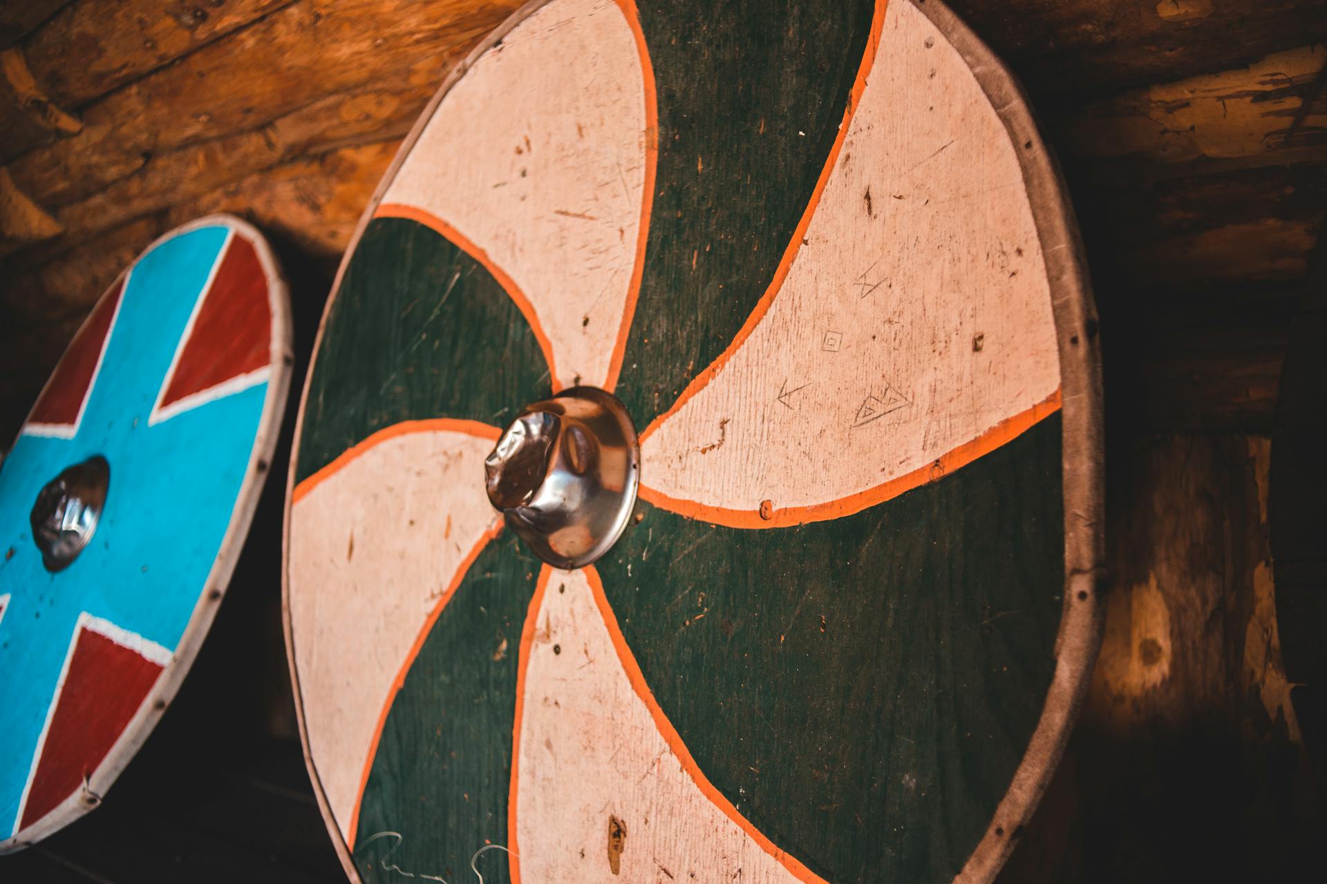 From below of various shabby circular Viking shields hanging on wall in aged wooden museum in Norstead