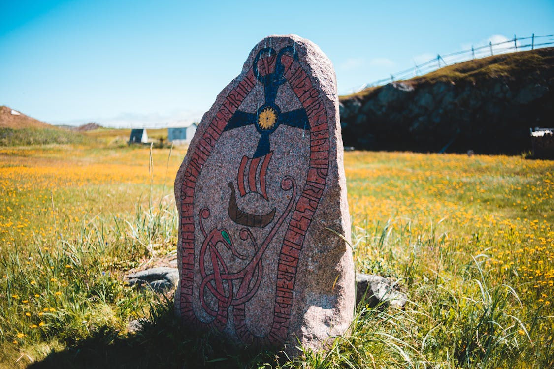 Free Aged Nordic runestone located on blooming field in countryside Stock Photo