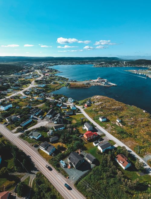 Free Aerial panoramic landscape of small village placed on green shore of blue bay in sunlight Stock Photo