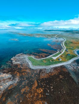 Breathtaking aerial view of a remote coastal landscape with winding roads and serene ocean.