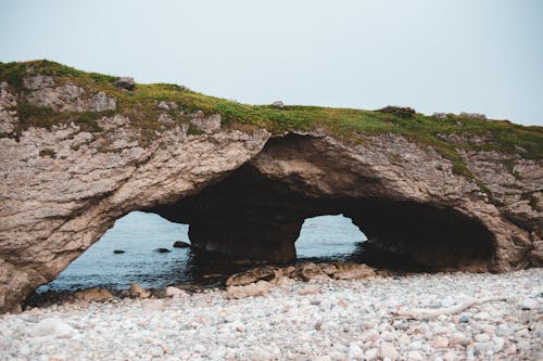 Free Mossy rocky arcs on remote beach Stock Photo