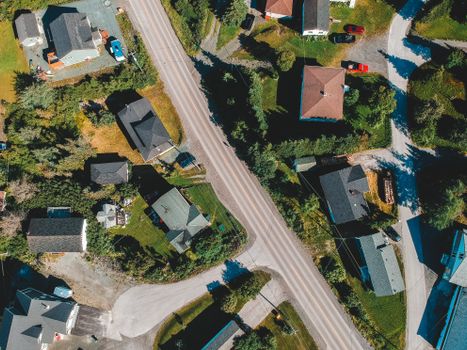 Aerial top view of house rooftops on green valley land with roadway in remote rural village