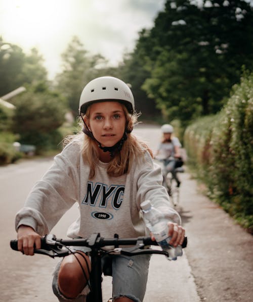 Young Woman Riding a Bicycle on Road Wearing a Helmet