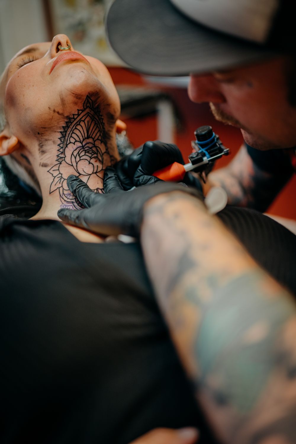 Close-up of a mandala throat tattoo being finished by the artist