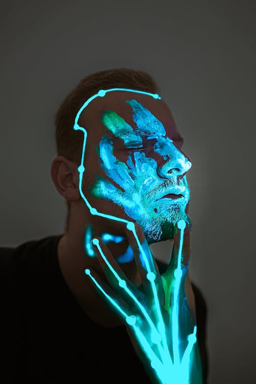 Unemotional man with glowing neon body art on face