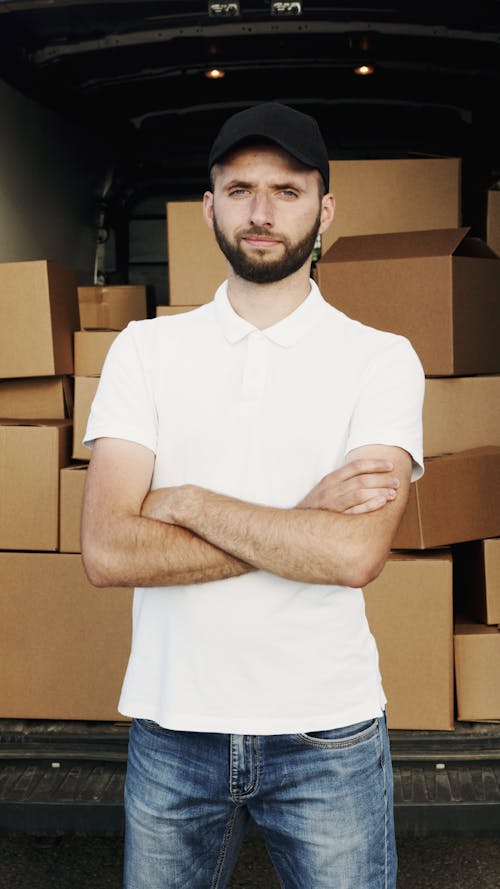 Free Man in White Polo Shirt Standing Near Brown Cargo Boxes Stock Photo