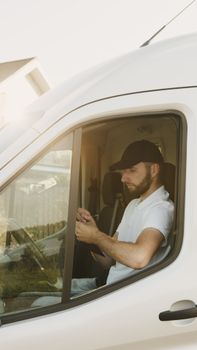 A delivery driver sits inside a white van using a mobile device, reflecting a professional courier service.