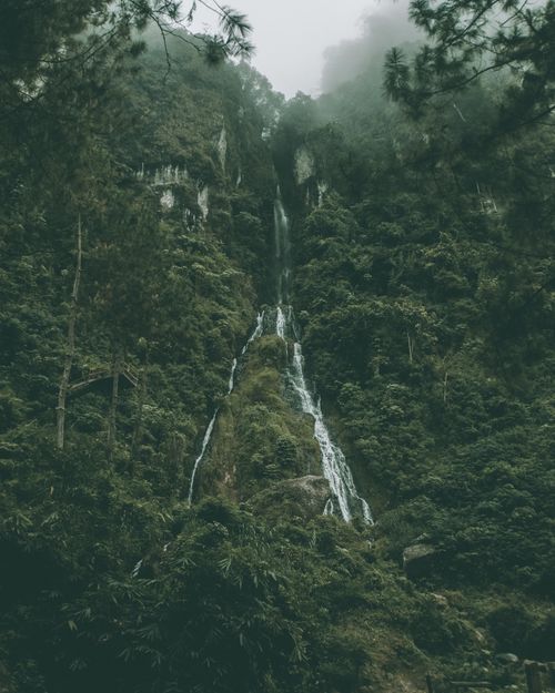 Free A breathtaking waterfall cascades down a fog-shrouded, verdant mountainside in Central Java, Indonesia. Stock Photo
