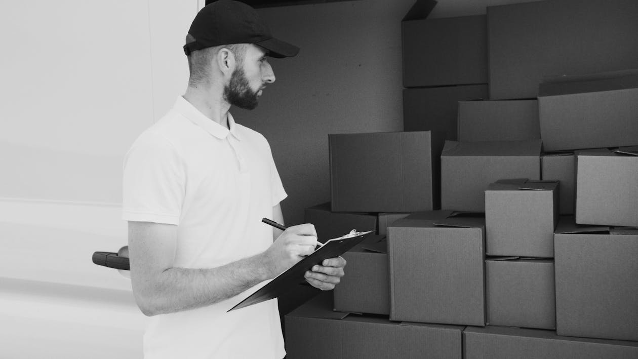 Grayscale Photo of Man Looking at Boxes · Free Stock Photo