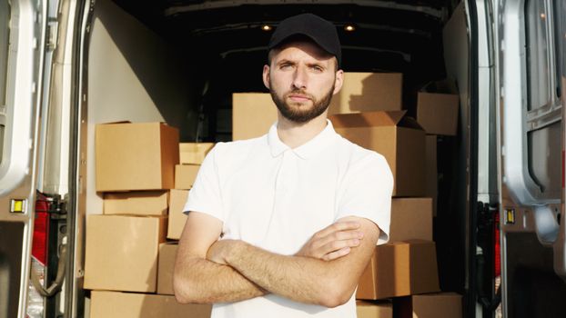 Courteous courier standing by van loaded with parcels and packages, ready for delivery service.