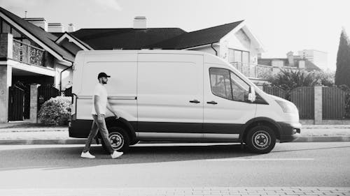 Monochrome Photo of Deliveryman Passing by the Panel Van