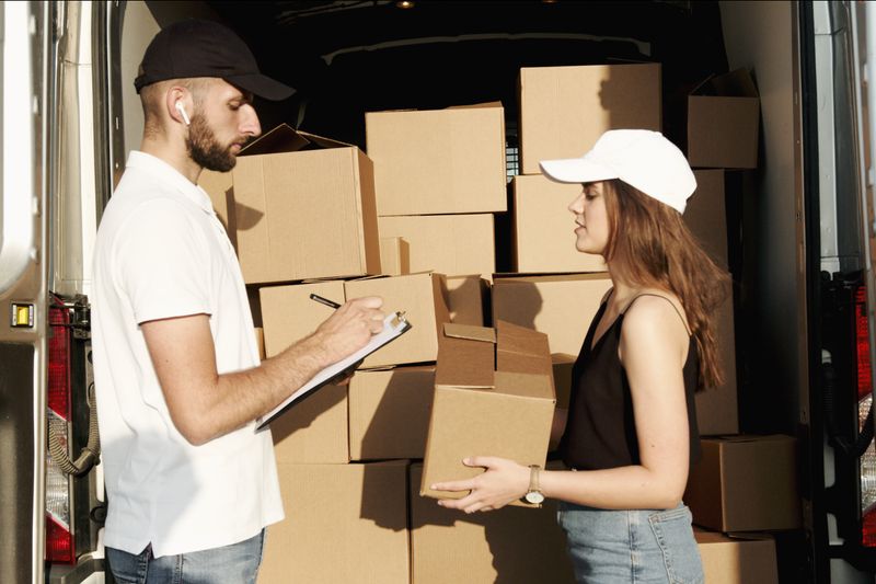 A male and female courier organizing packages in a delivery truck for efficient shipment.