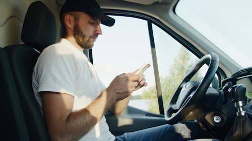 Man Sitting Inside the Vehicle while Using His Smartphone
