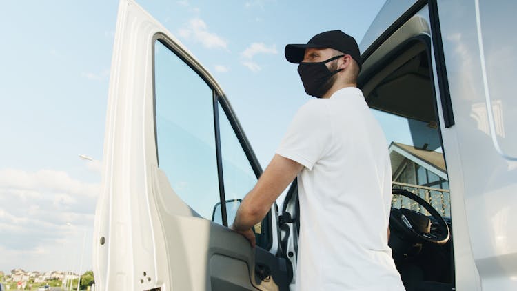 Man In White Polo Shirt Standing By The Vehicle Door