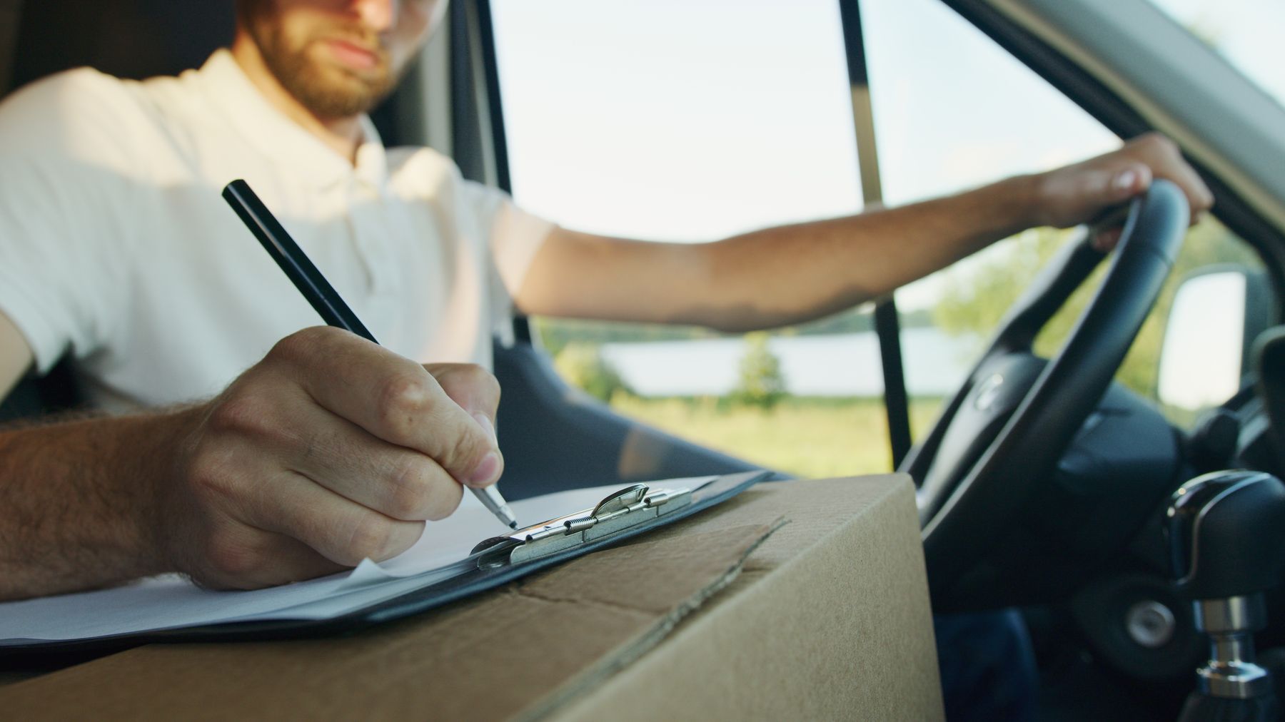 Driver writing transportation information on a clipboard inside a vehicle