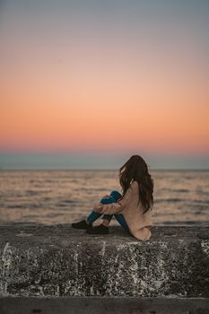 在开普敦的防浪堤上，一名妇女正坐着享受海上宁静的日落