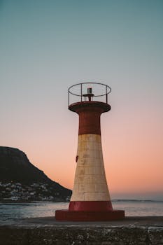Lighthouse in Cape Town at sunset with beautiful ocean view, capturing warm sunset colors.