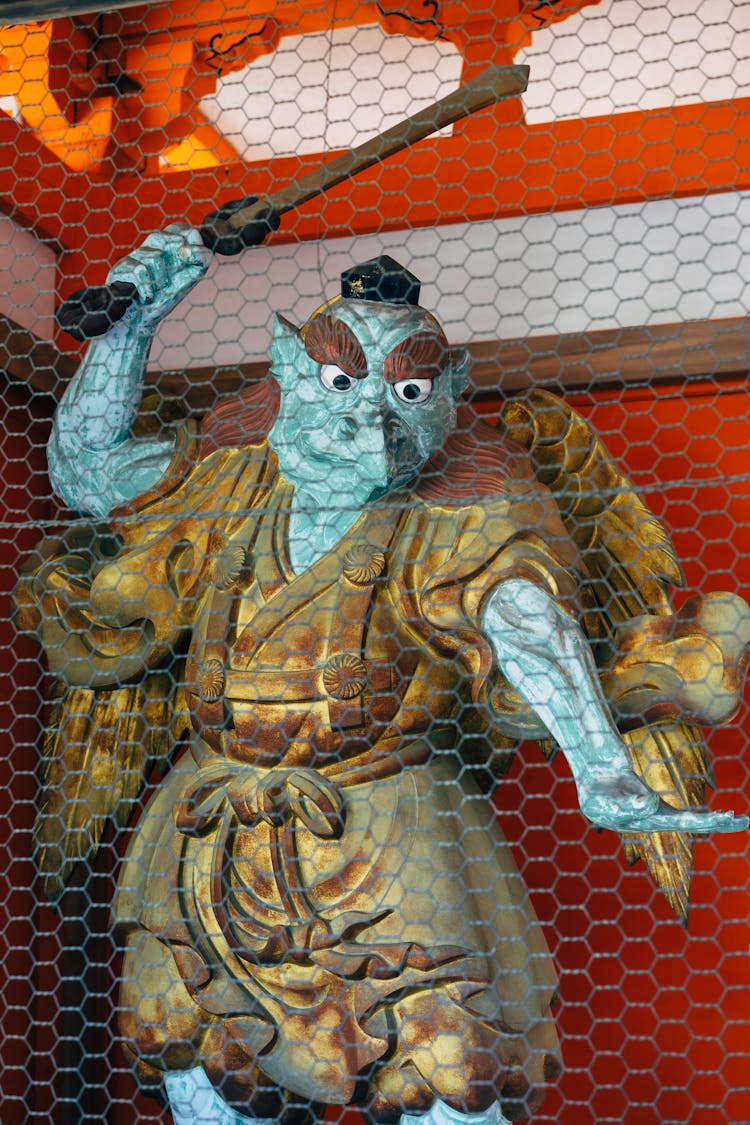 Japanese Statue Behind A Mesh Wire