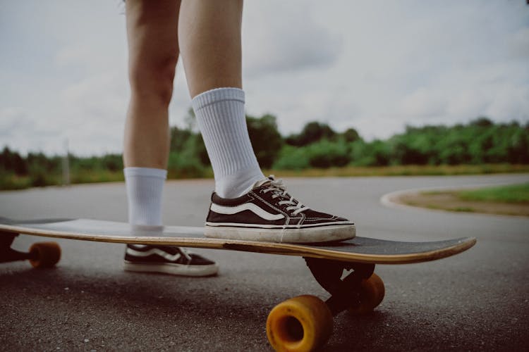 Person In Black And White Vans Low Top Sneakers Riding Skateboard