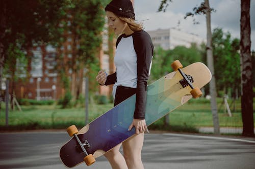 Selective Focus Photo of a Woman Carrying a Longboard