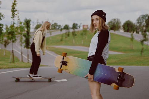 gratis Vrouw In Zwart Wit Shirt Met Lange Mouwen Met Blauw En Geel Skateboard Stockfoto