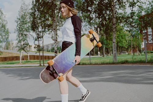 Woman in White and Black Long Sleeve Shirt Holding a Longboard