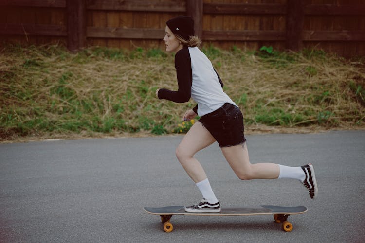 Woman In White T-shirt And Black Shorts Skateboarding