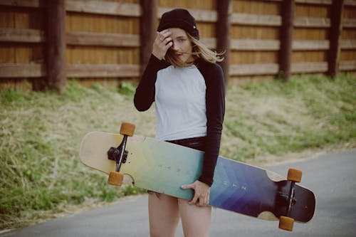 gratis Vrouw In Wit Shirt Met Lange Mouwen En Blauwe Denim Rok Met Skateboard Stockfoto