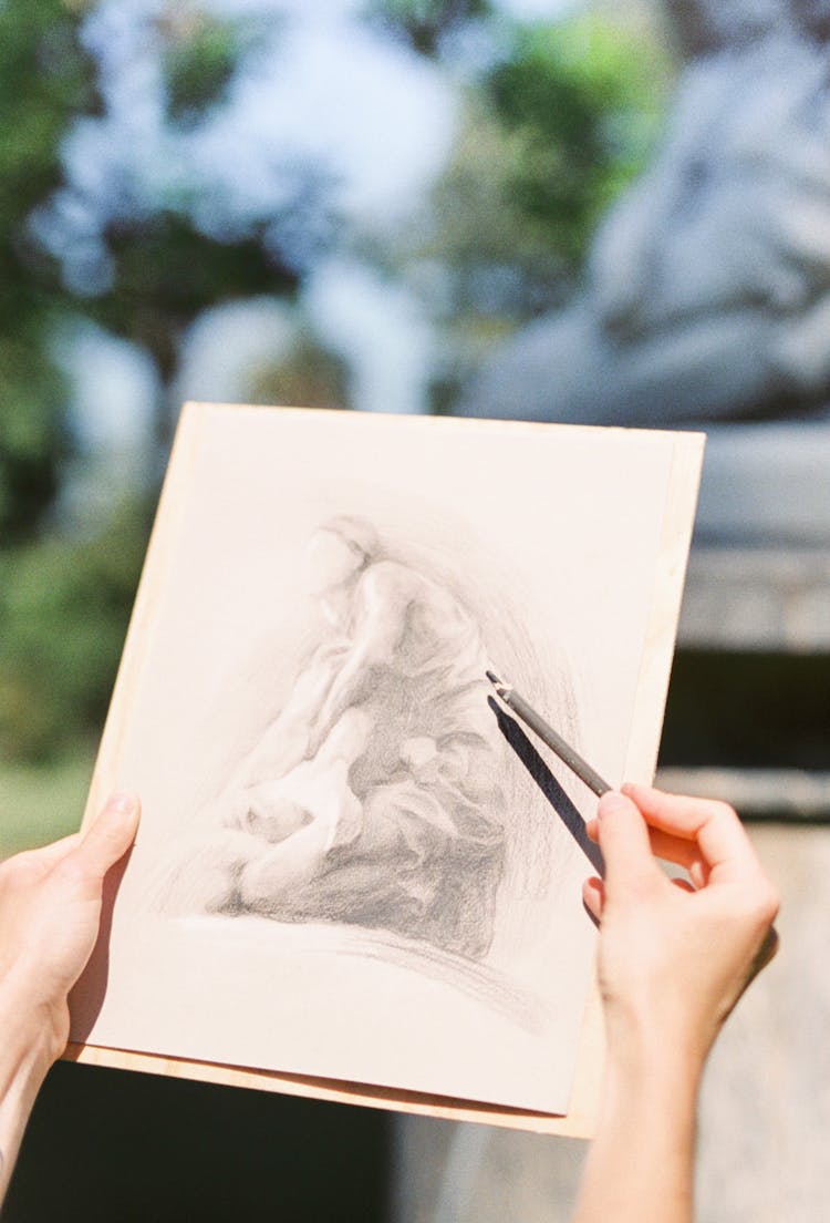 Person Holding Black Pencil Drawing On White Paper