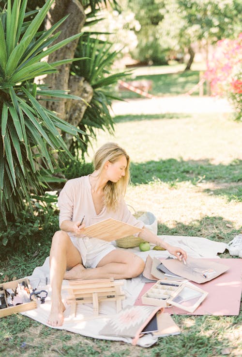 Woman in White Long Sleeve Shirt Sitting on Ground