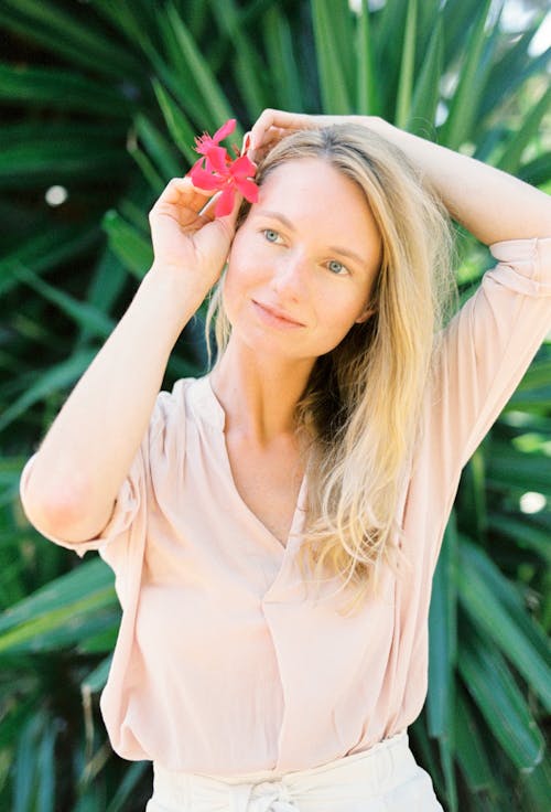 Woman Clipping Red Flower on Her Ear