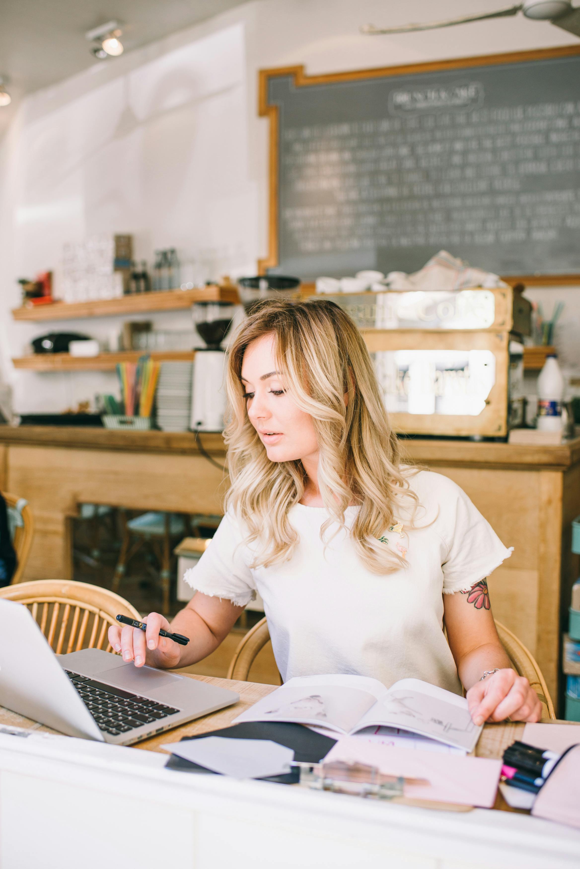 一位金发女子在舒适的自助餐厅里用笔记本电脑工作