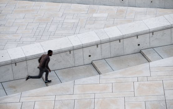 Dynamic shot of a man running up modern urban steps in Oslo. High-angle view.