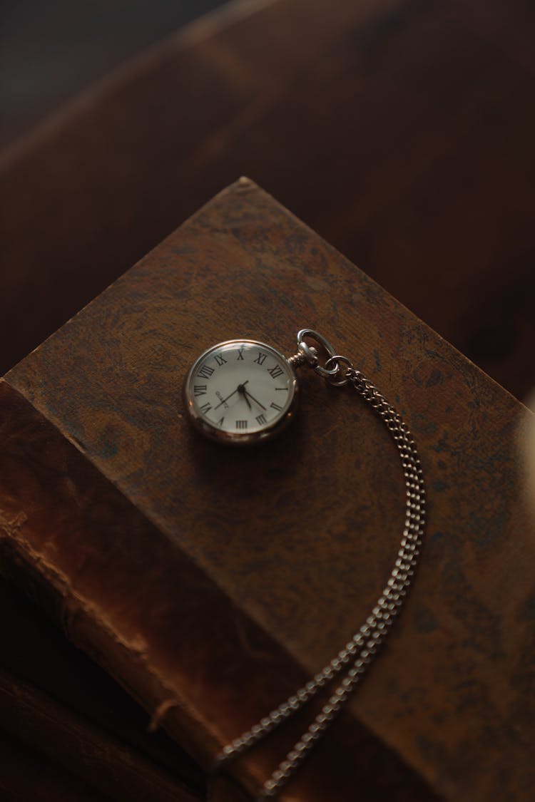 Old Pocket Watch On Top Of An Old Book