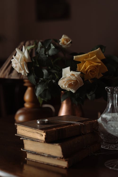 Free Stack of Antique Books beside Bouquet of Roses Stock Photo