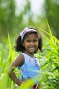 Little Girl Smiling and Standing in High Green Grass