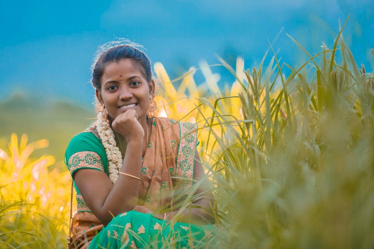 Smiling Girl In Traditional Clothing Sitting In Grass