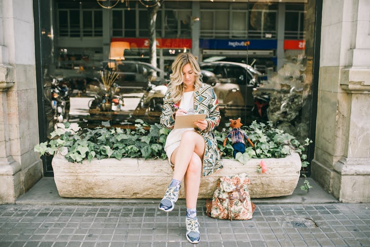 Beautiful Woman Sitting On A Plant Box