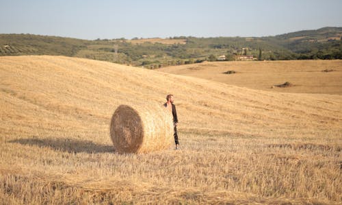 Man Standing on Field By a Bale