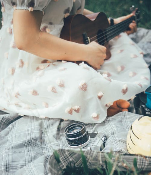 Crop woman playing ukulele on blanket