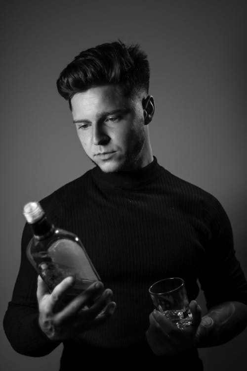 Monochrome Photo of Man Holding a Bottle of Whisky