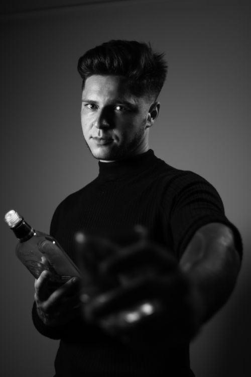 Free A monochrome portrait of a man holding a bottle, conveying a dramatic mood. Stock Photo