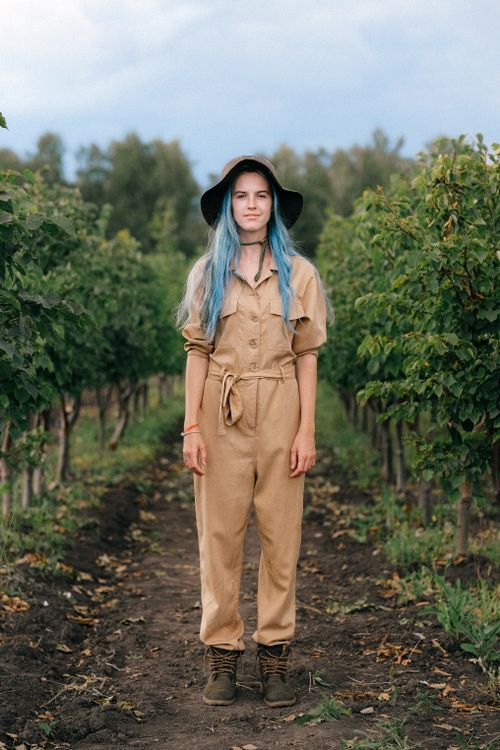 Free Woman gardener with blue hair in overalls standing among vineyard rows. Stock Photo