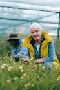 老妇人在温室里愉快地打理花草，四周鲜花环绕