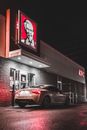 White car at window of cafe drive through ordering fast food at night time