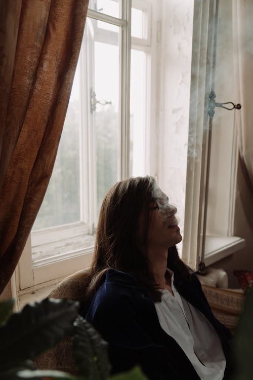 Man in Blue Jacket Sitting Beside Window