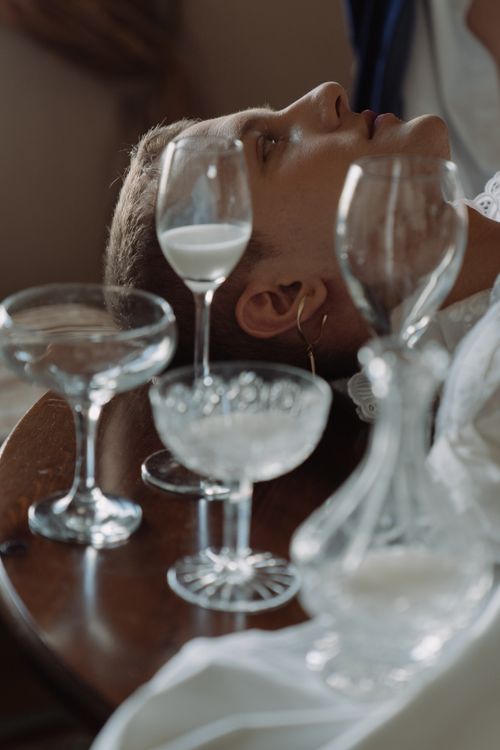 Free A refined portrait of a man with crystal glassware filled with milk on a wooden table, exuding a noble and artistic ambiance. Stock Photo
