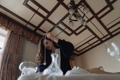 Woman in Blue Long Sleeve Shirt Sitting on White Bed