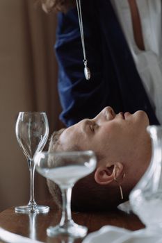 这幅优雅的肖像描绘了一位以催眠为主题的男人，突显了玻璃器皿的美感